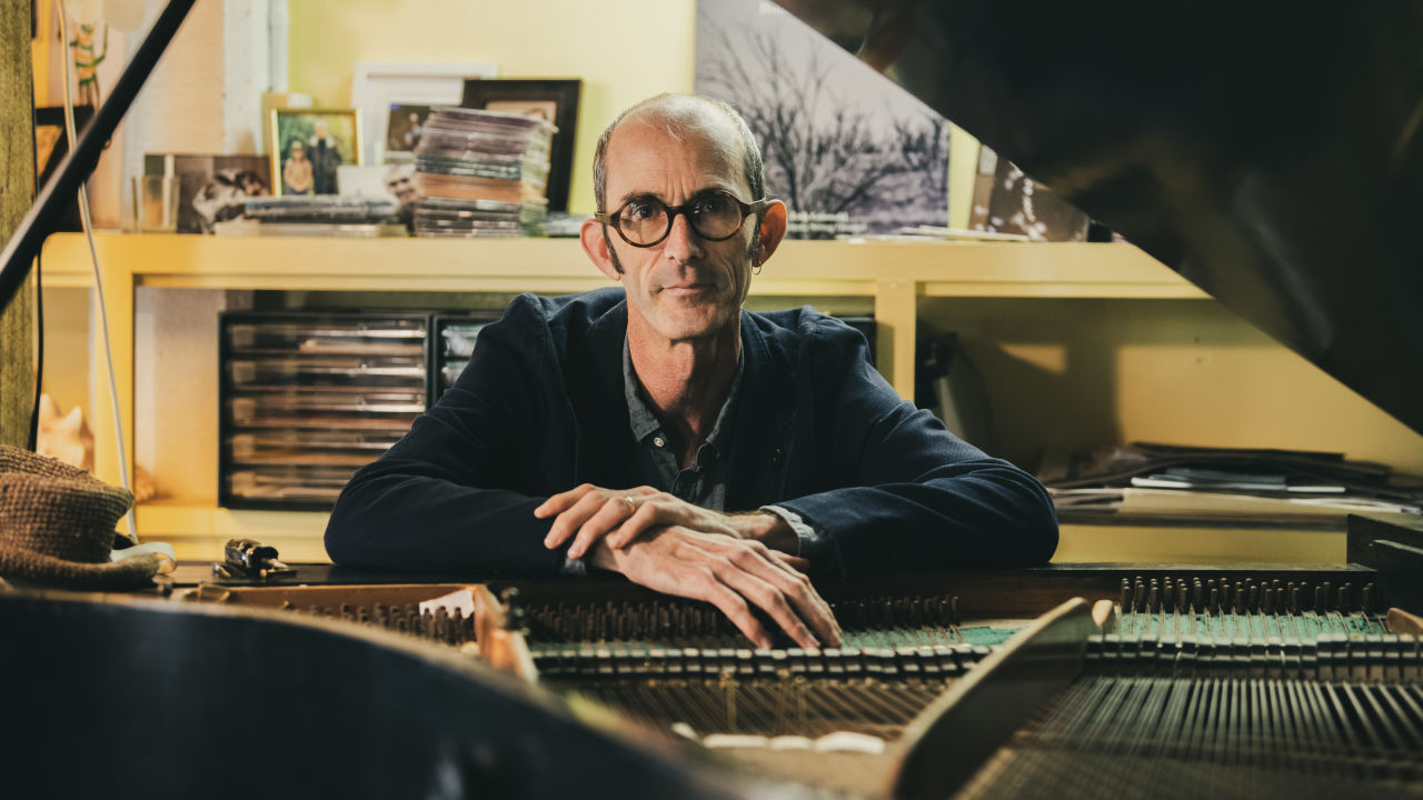 Erik Griswold sitting behind a piano looking at the camera.