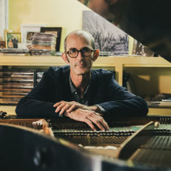 Erik Griswold sitting behind a piano looking at the camera.