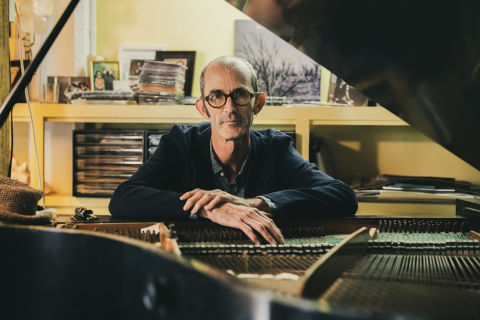 Erik Griswold sitting behind a piano looking at the camera.